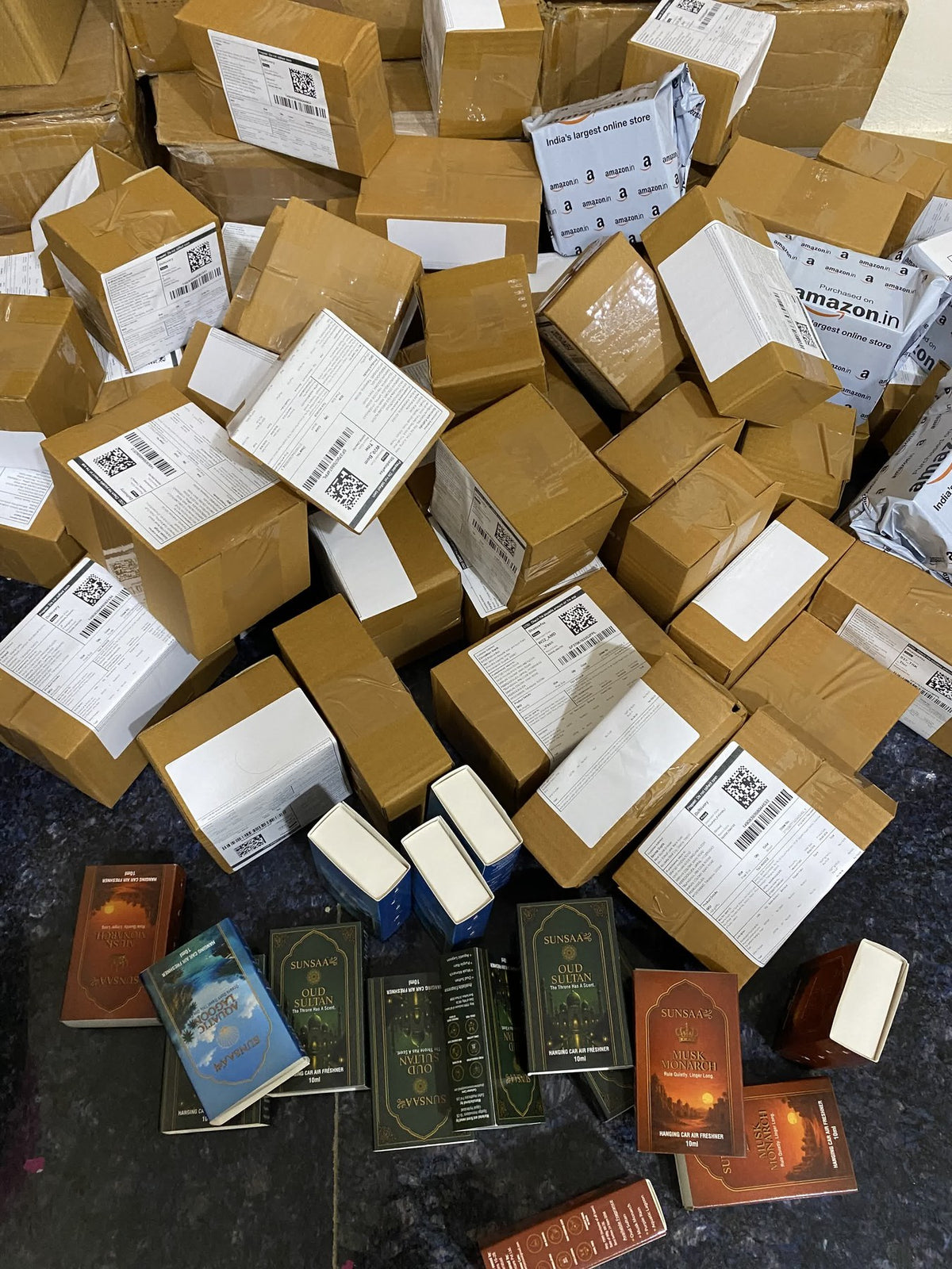 SUNSAA Oud Sultan and Musk Monarch boxes beside a stack of packed and labelled parcels ready to ship